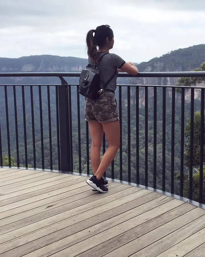 Femme en tenue de sport, tenant des haltères, posant de profil.