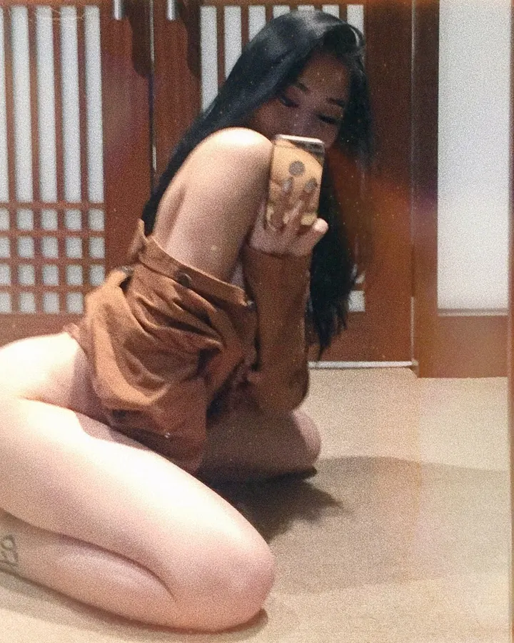 Femme asiatique aux cheveux bruns-noirs, yeux marrons, peau blanche, sourire franc, vêtue d'une tenue moderne dans un cadre urbain.