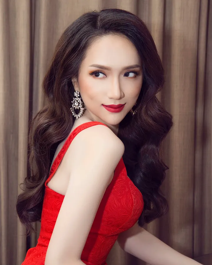 Femme asiatique en robe rouge, cheveux noirs bouclés, regardant vers le côté, boucles d'oreilles élégantes