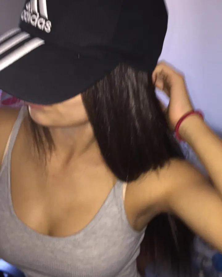 Femme indienne aux cheveux noirs longs, vêtue d'un haut léopard, regardant directement l'appareil dans un cadre sombre, expression neutre.